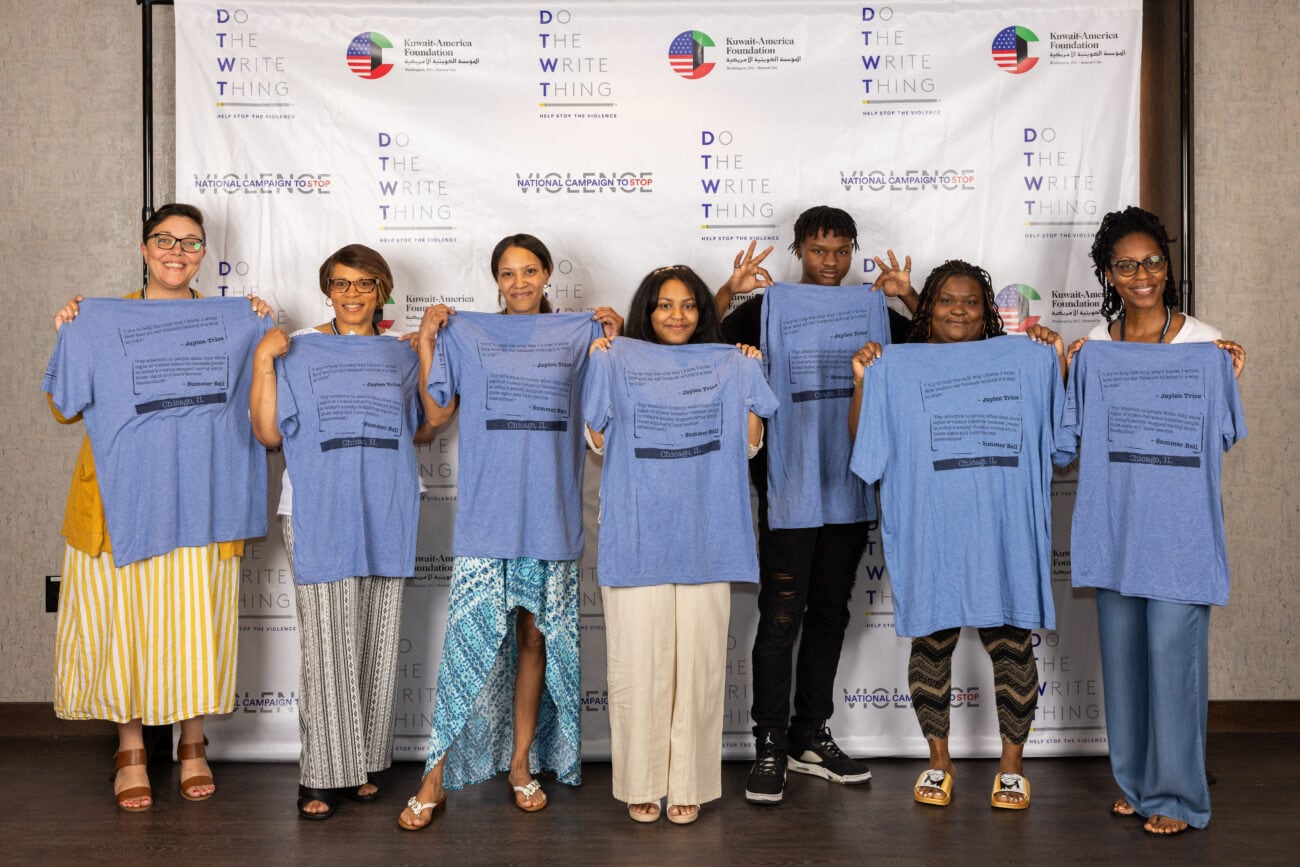 Do the Write Thing Chicago ambassadors hold up T-shirts at summit