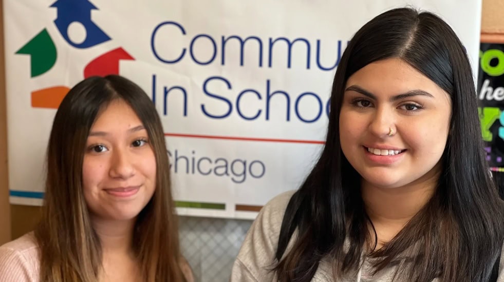 Two high school seniors with CIS logo in background