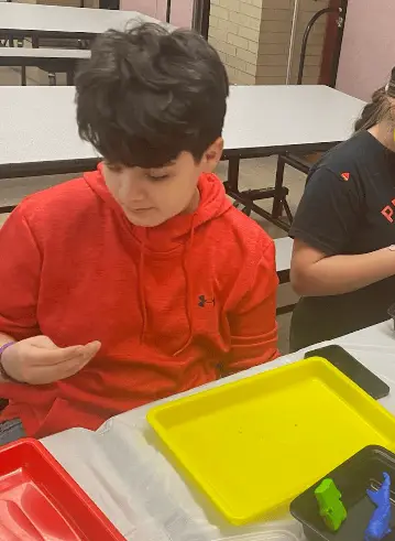 A male student examines an object as part of an art making activity