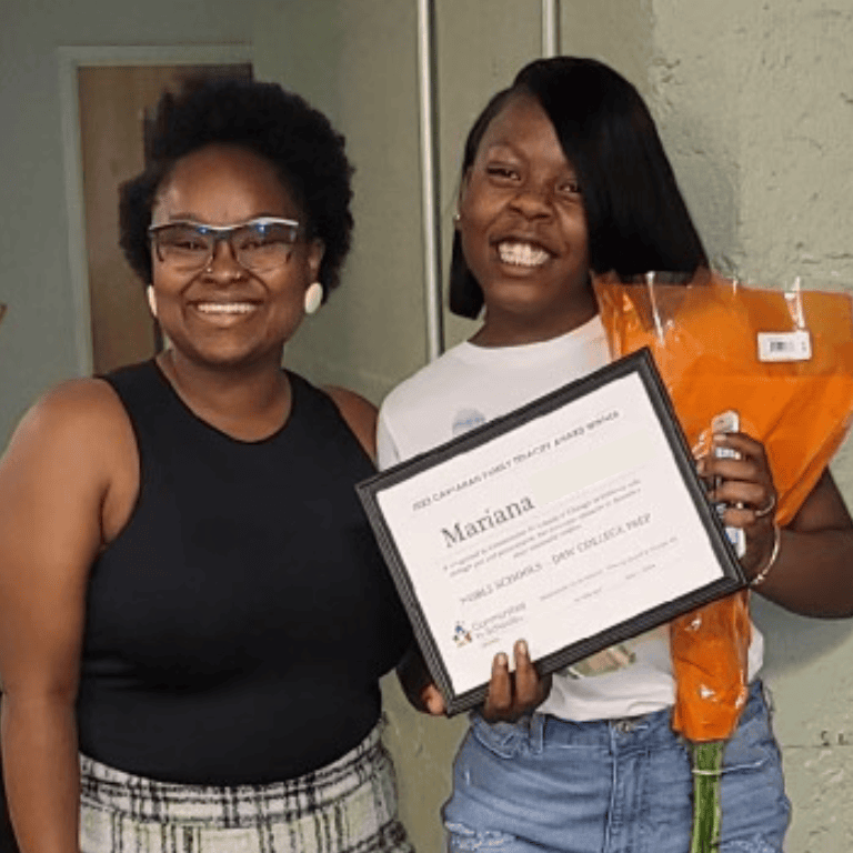 Student and Support Manager smile; student holds certificate and flowers