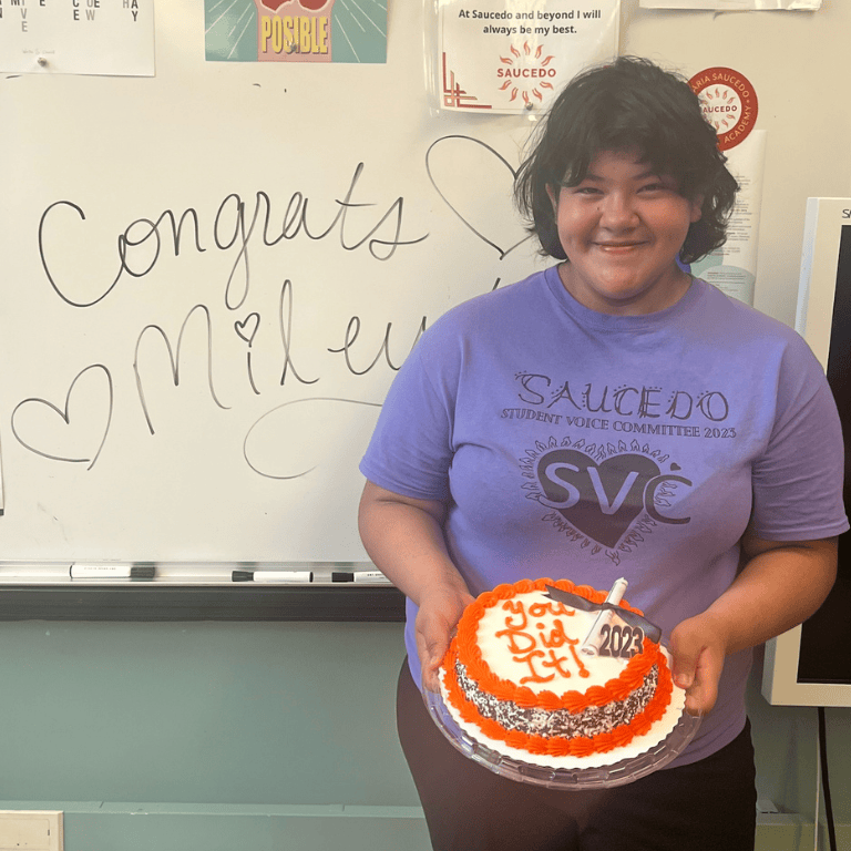 Student holds up cake with graduation cap