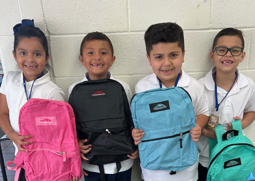 Students hold up new backpacks
