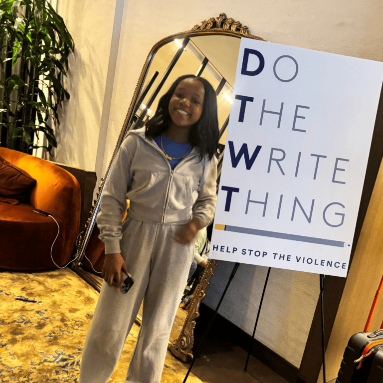 Jade stands next to Do the Write Thing sign
